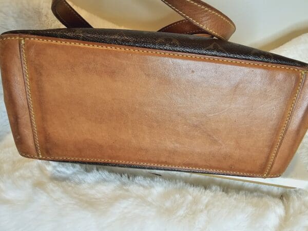 A brown purse sitting on top of a white fur.