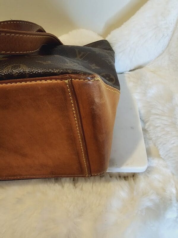 A brown purse sitting on top of a white blanket.