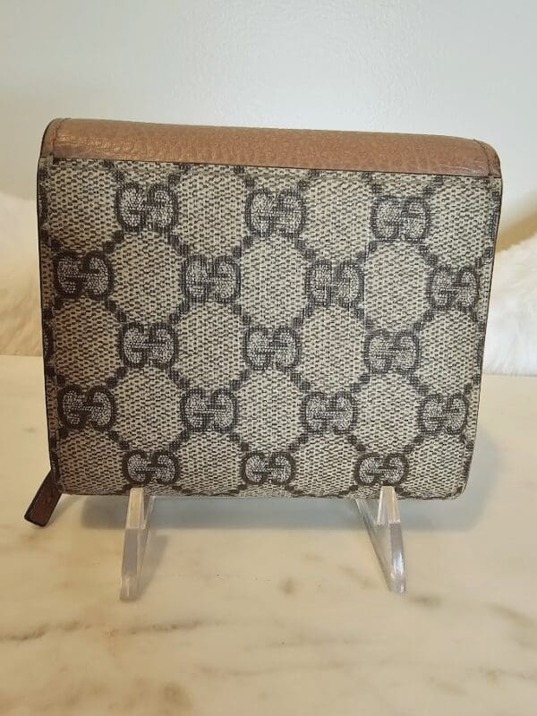 A brown and white gucci wallet sitting on top of a table.