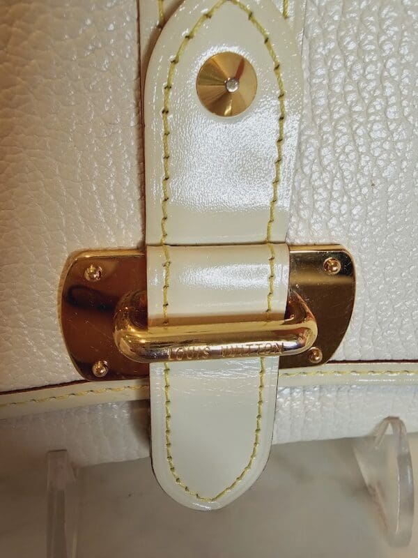 A close up of the handle on a white purse