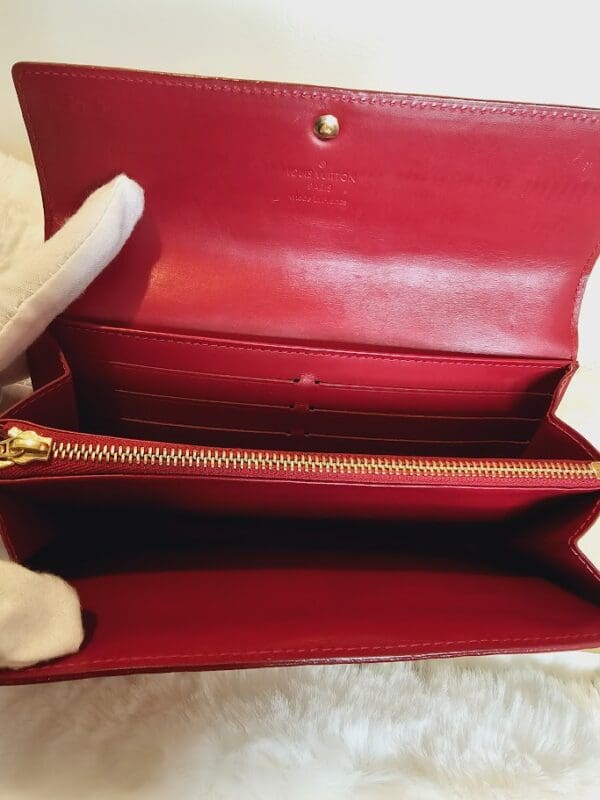 A red purse is open and has two white gloves on it.