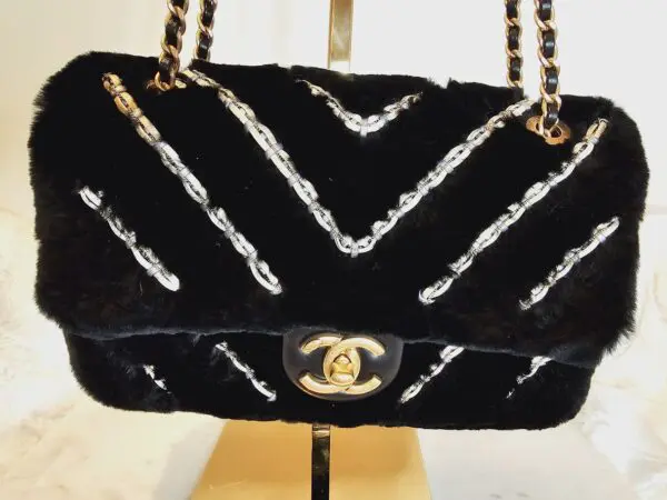 A black purse with silver and gold chain straps.