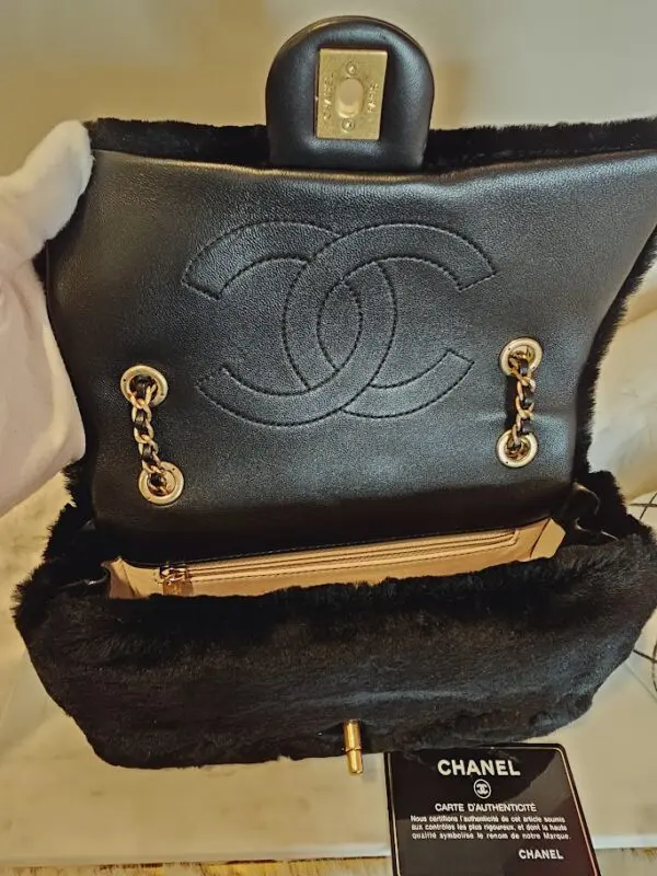 A black purse with fur inside of it