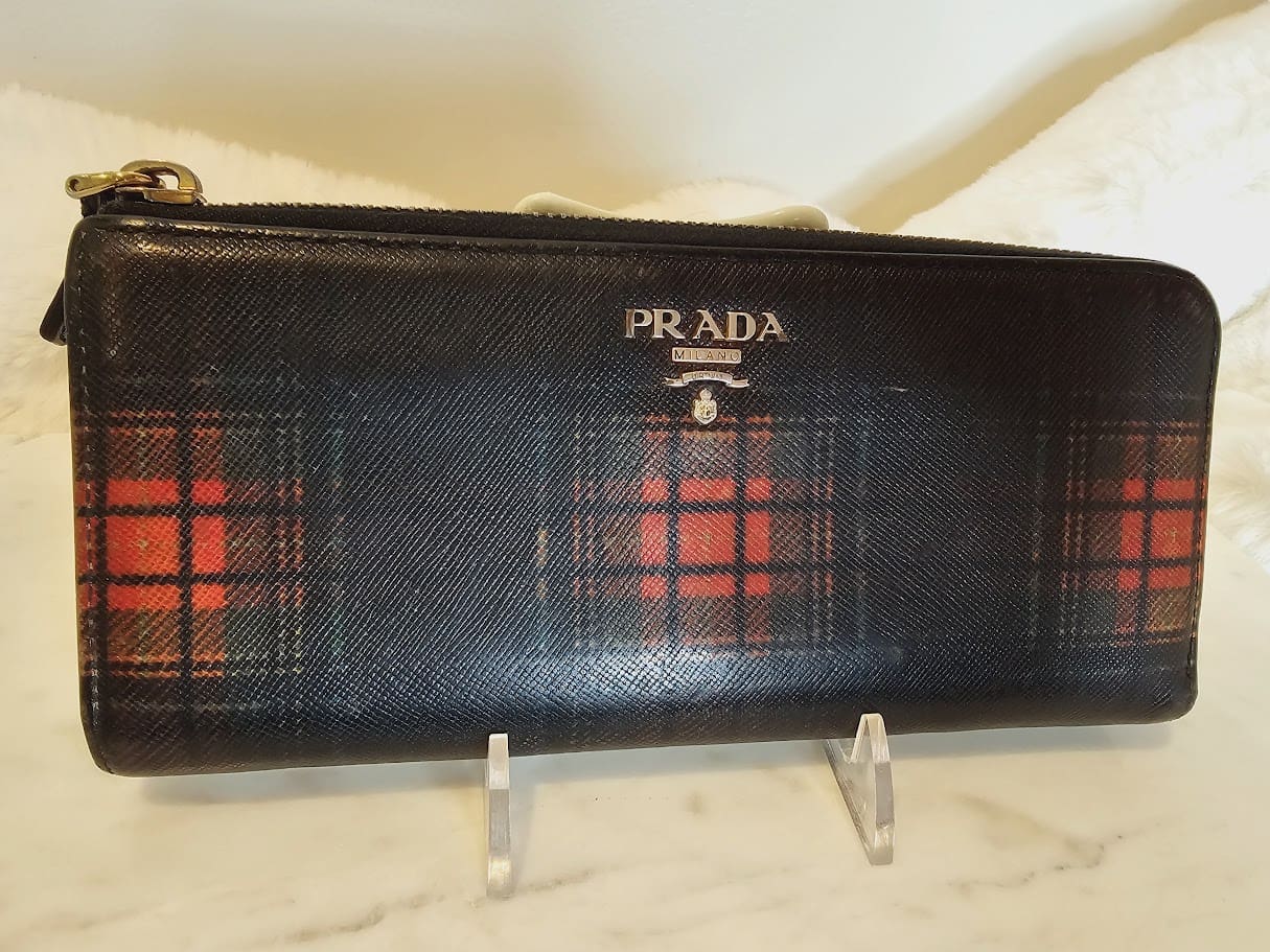 A black and red plaid prada wallet sitting on top of a counter.