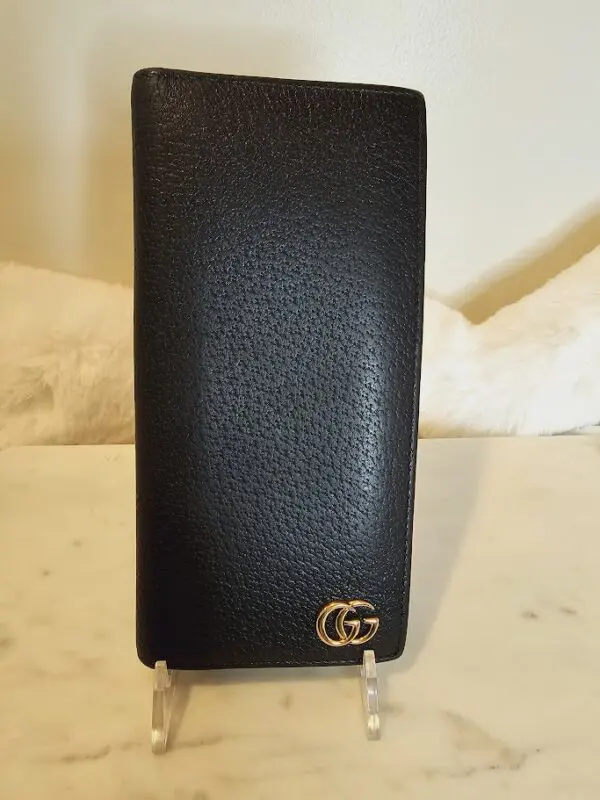 A black wallet with gold accents on top of a table.