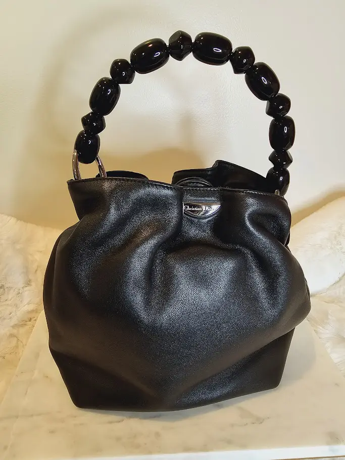 A black purse with wooden handle on top of table.