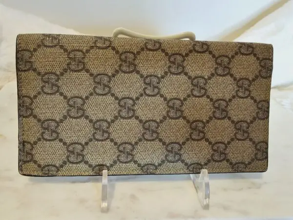 A brown and beige gucci wallet sitting on top of a counter.