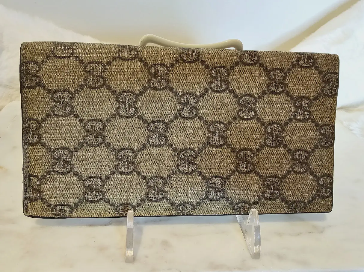 A brown and beige gucci wallet sitting on top of a counter.