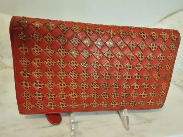 A red purse with gold and black pattern on it.