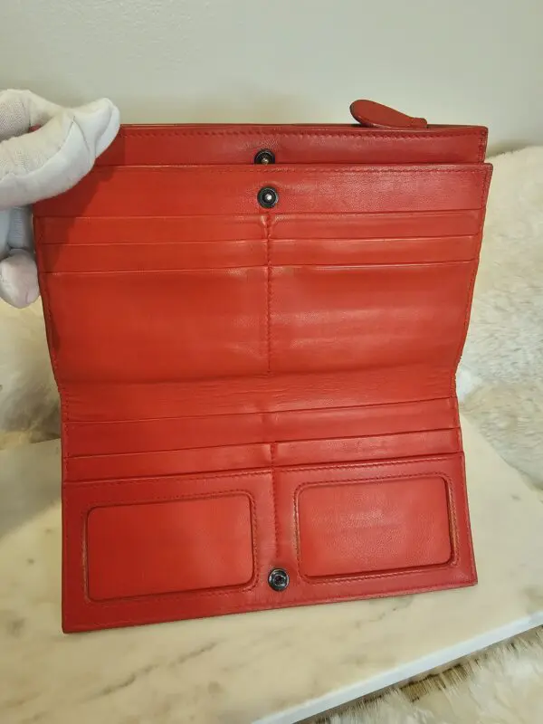 A red wallet is open and has two pockets.