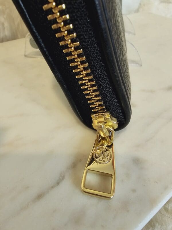 A close up of the zipper on a black wallet