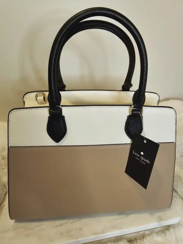 A white and brown purse sitting on top of a bed.