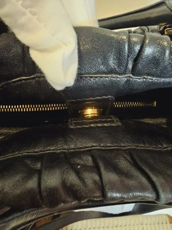 A close up of the zipper on a leather bag