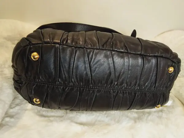 A black purse sitting on top of a white fur.