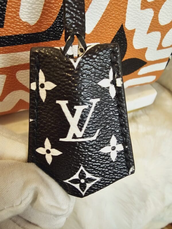 A black and white louis vuitton bag sitting on top of a bed.